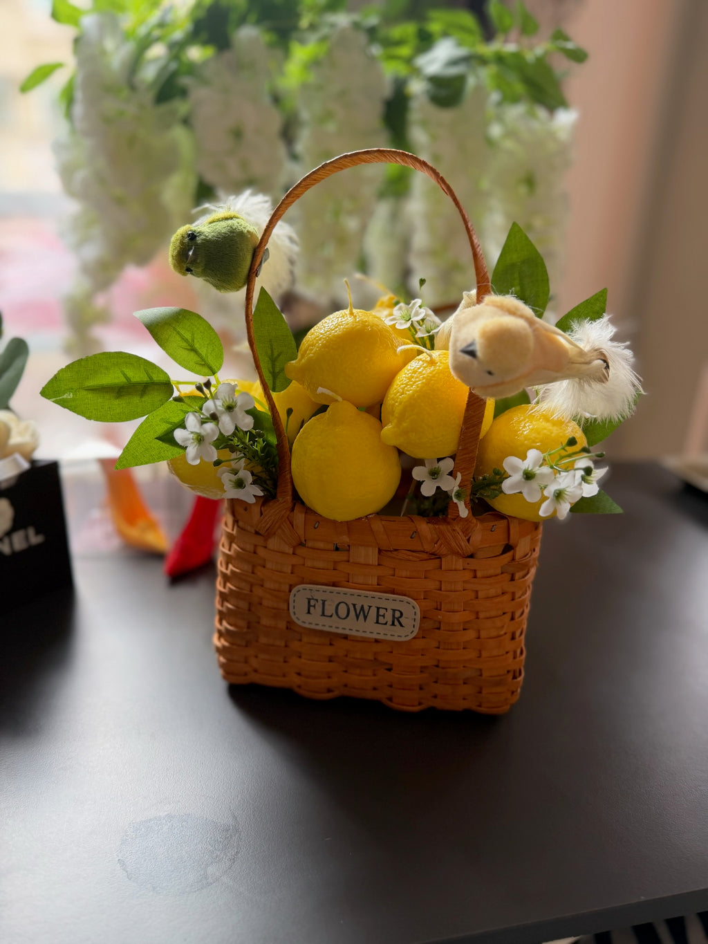 Плетена кошница с лимони, птичка, зелени листа и бели цветчета; етикет „FLOWER“