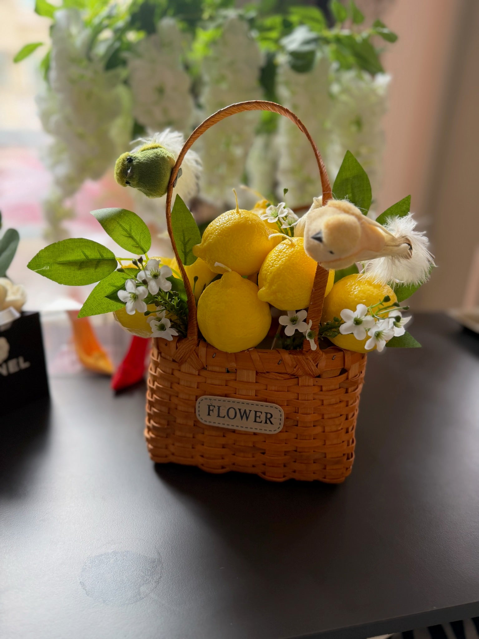Плетена кошница с лимони, птичка, зелени листа и бели цветчета; етикет „FLOWER“