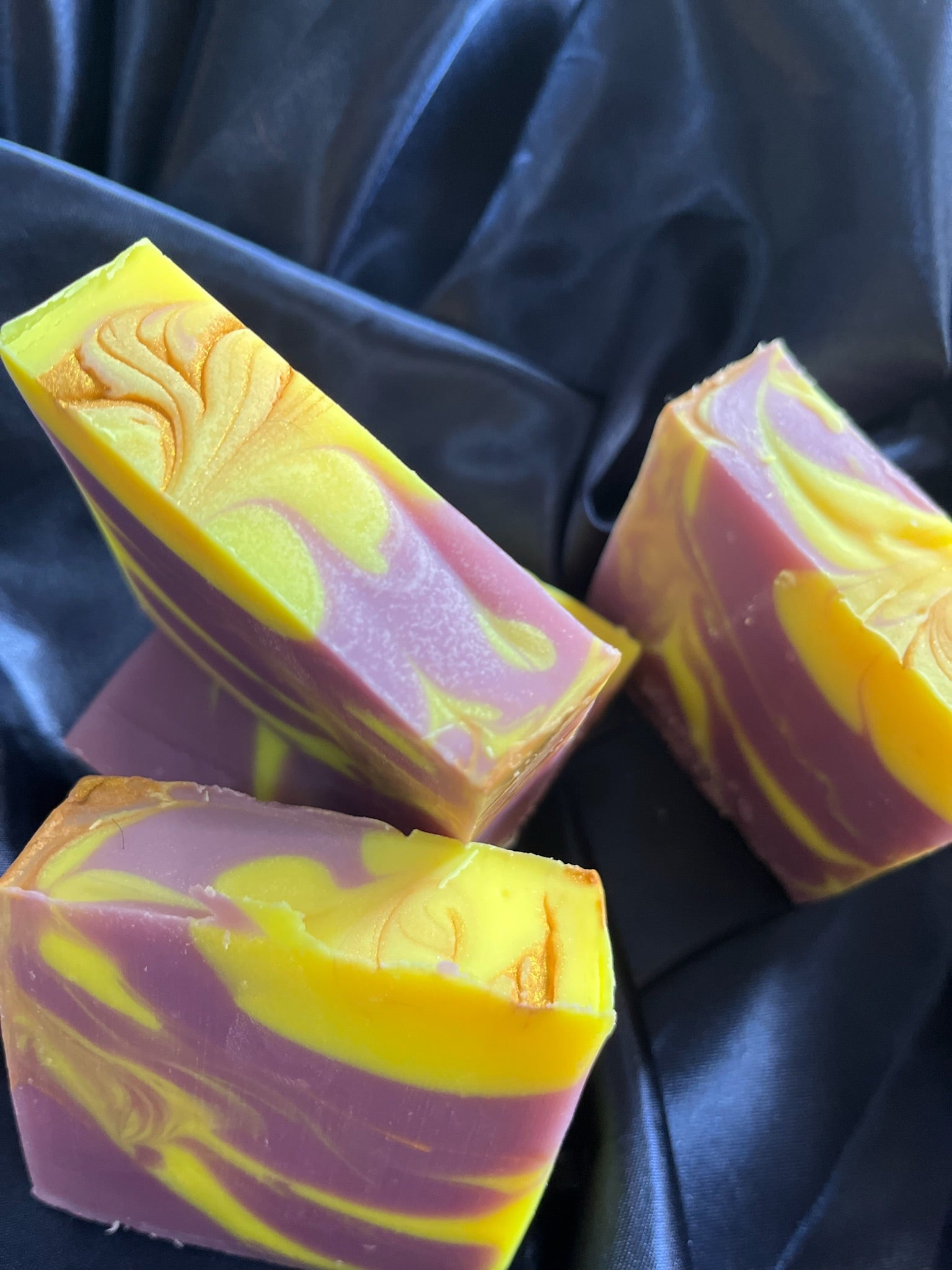 Pair of handmade soap bars, purple and yellow marbling with decorative swirl emboss on top