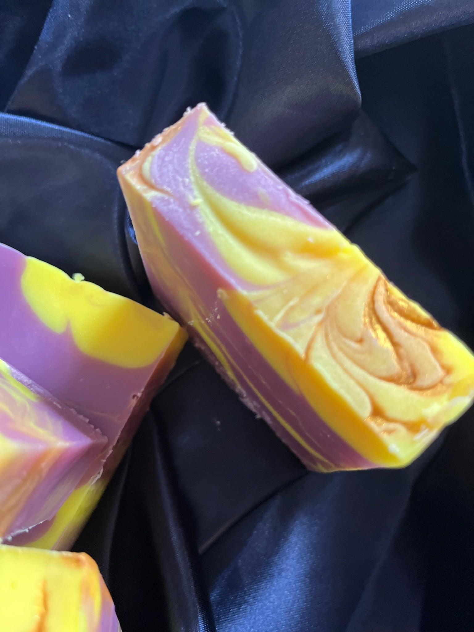 Soap bars with purple and yellow swirl pattern, one bar showing embossed rose-like detail