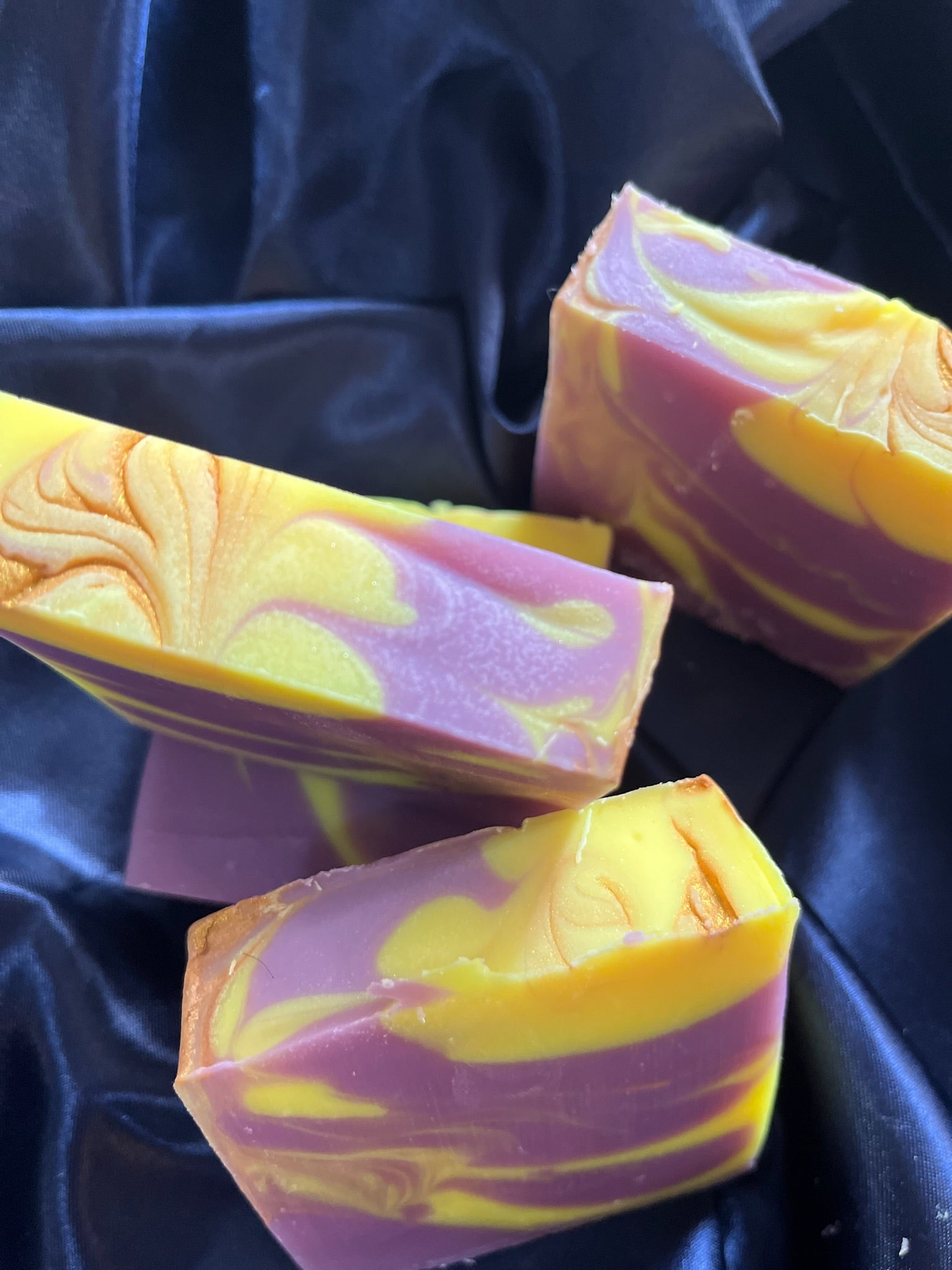 Colorful handmade soap bar, purple and yellow with swirled pattern and carved top detail