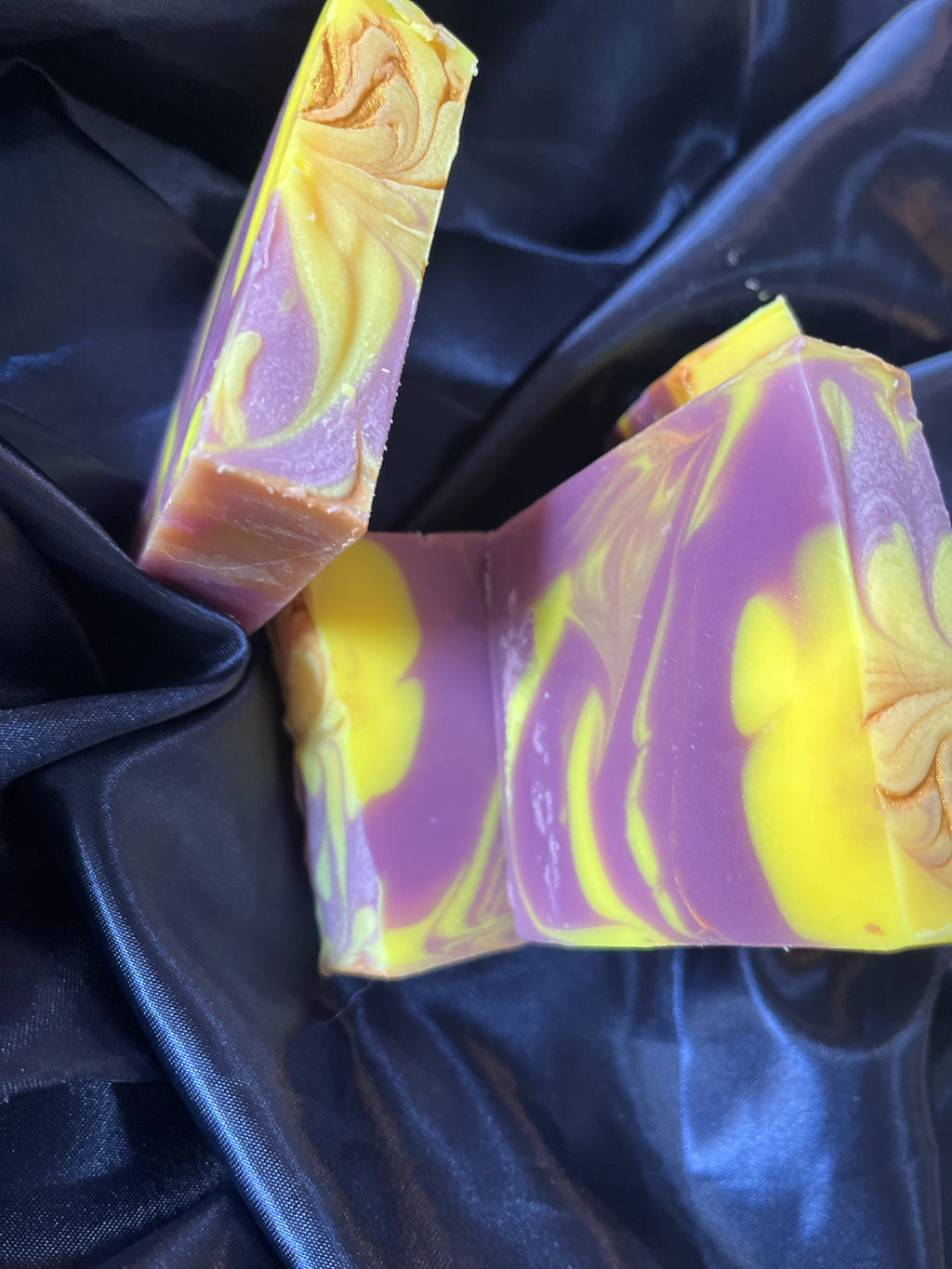 Purple and yellow handcrafted soap bars, marbled streaks and embossed swirl details on faces