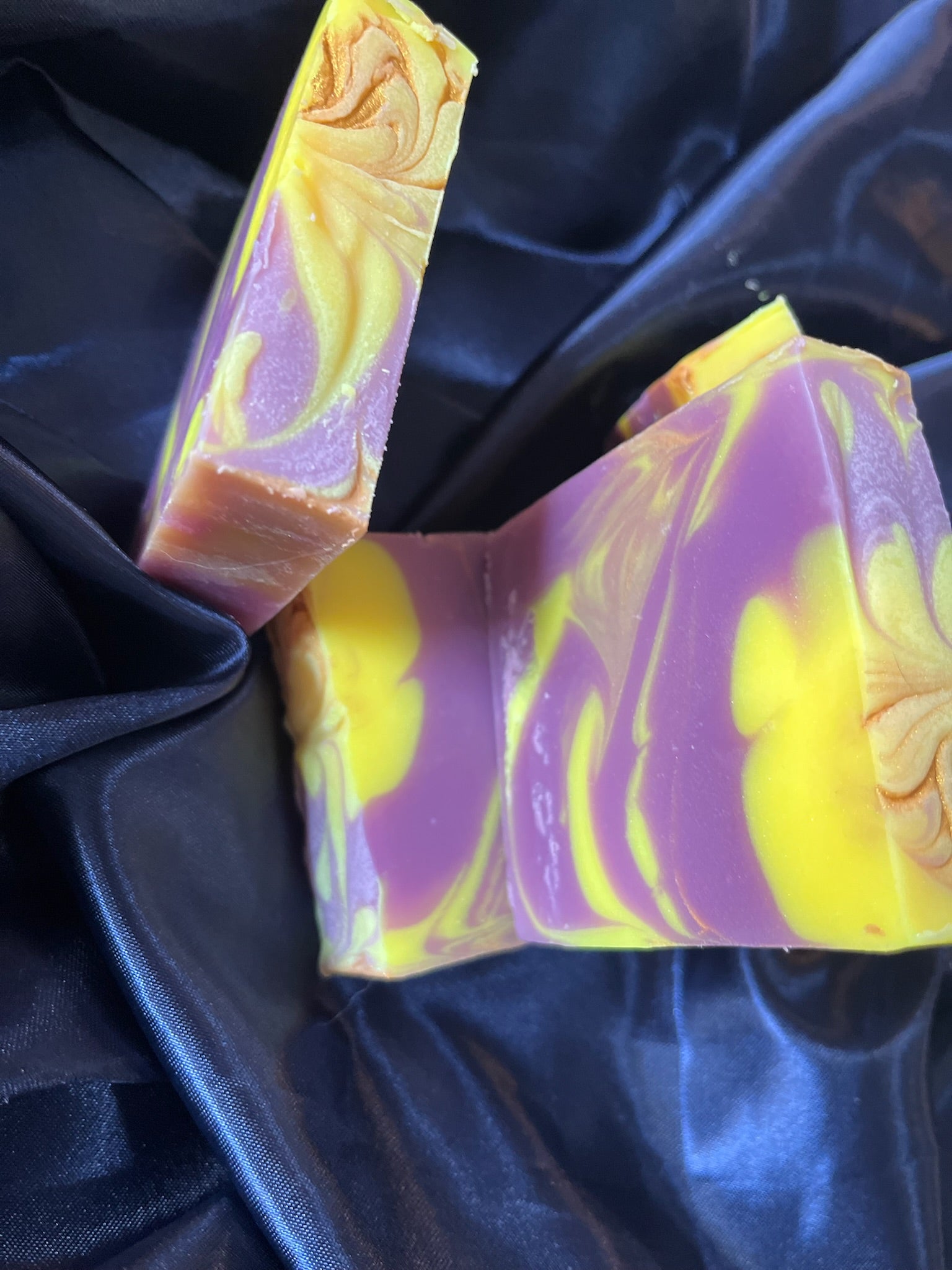 Purple and yellow handcrafted soap bars, marbled streaks and embossed swirl details on faces