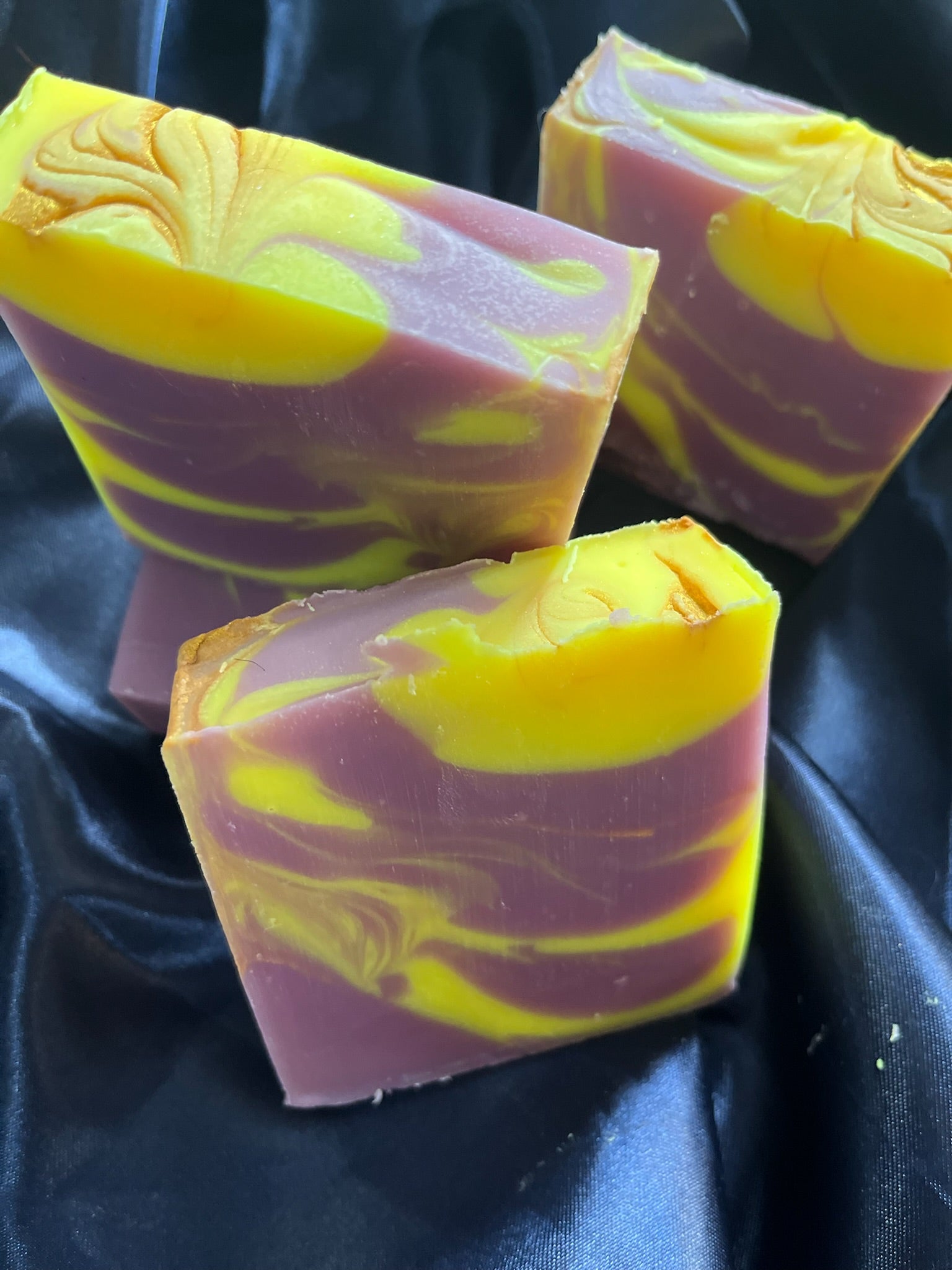 Soap bars with purple sides and bright yellow accents, marbled waves and embossed swirl