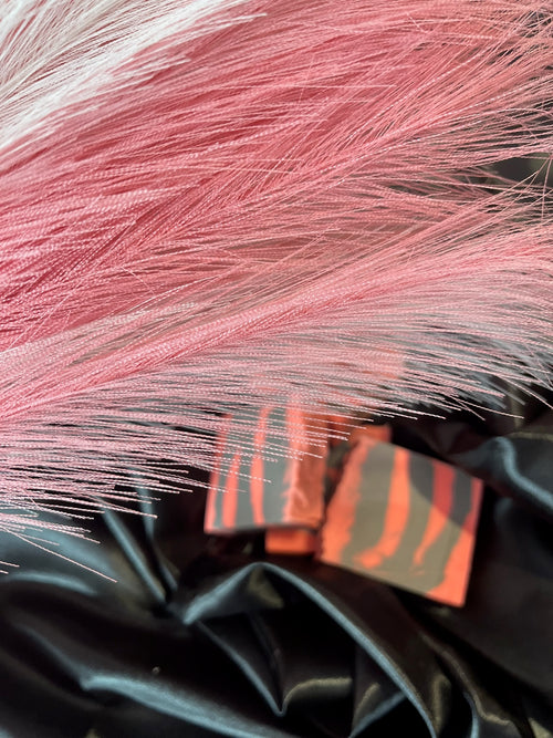 Pink-coral and gray striped soap pieces stacked on dark satin
